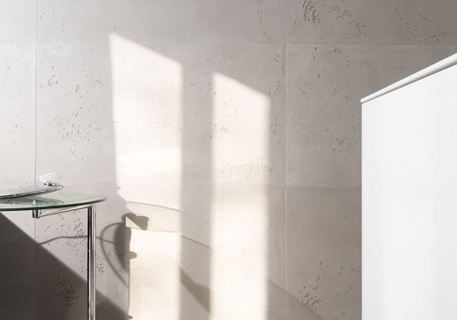 Lichtspiel auf strukturierter mineralischer Wand neben Glastisch