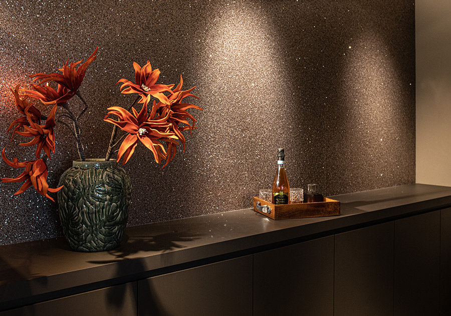 Glitzernde Wandfläche mit Vase und Tablett im elegant beleuchteten Showroom