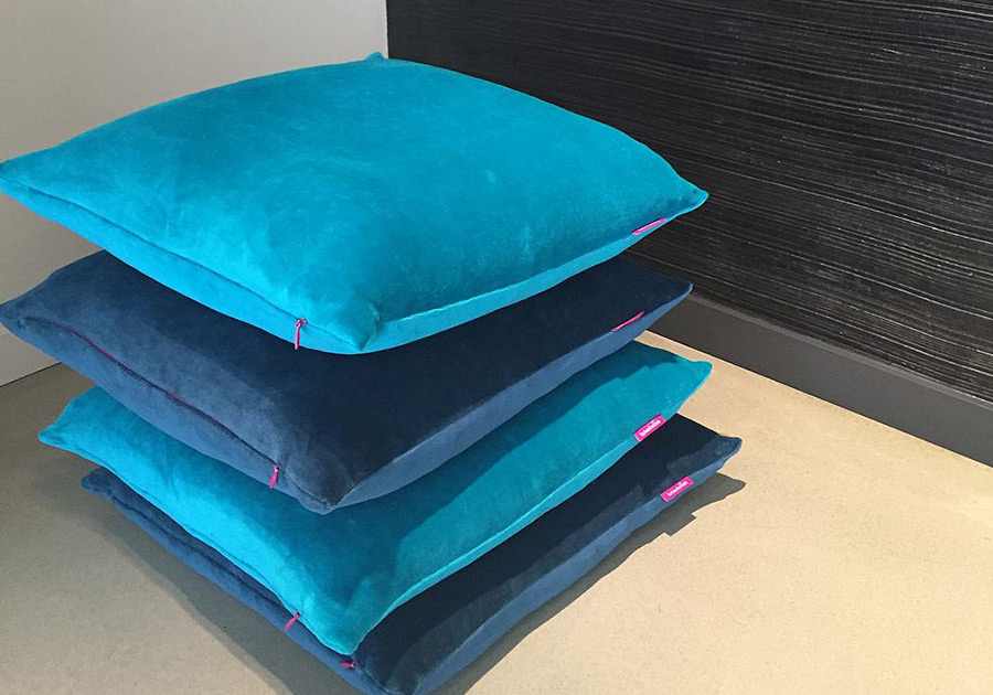 Farbiger Kissenstapel mit leuchtenden Blautönen auf hellem Boden