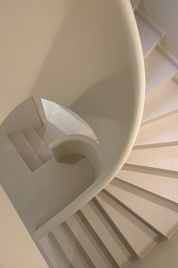 Geschwungene Treppe mit fugenloser, heller Oberfläche und moderner Architektur